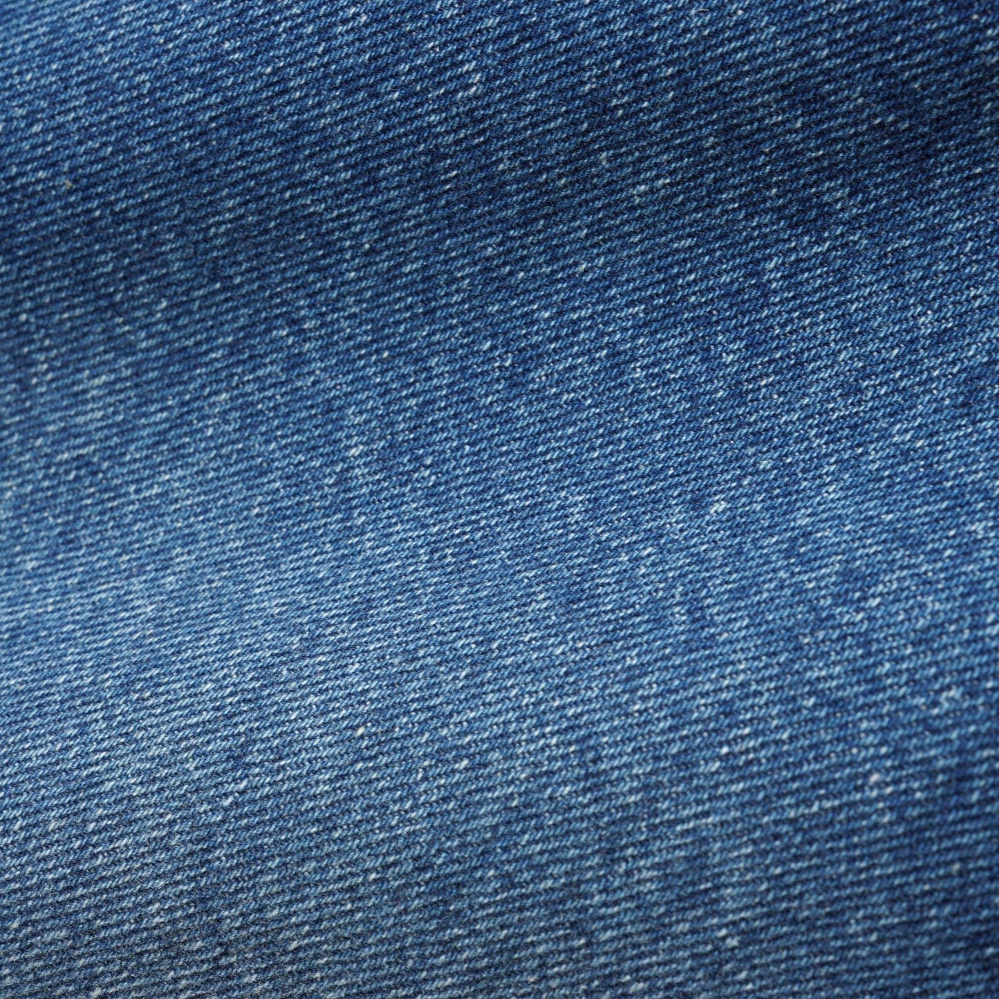 A close-up texture shot of blue denim fabric, showing the detailed twill weave and subtle fading.