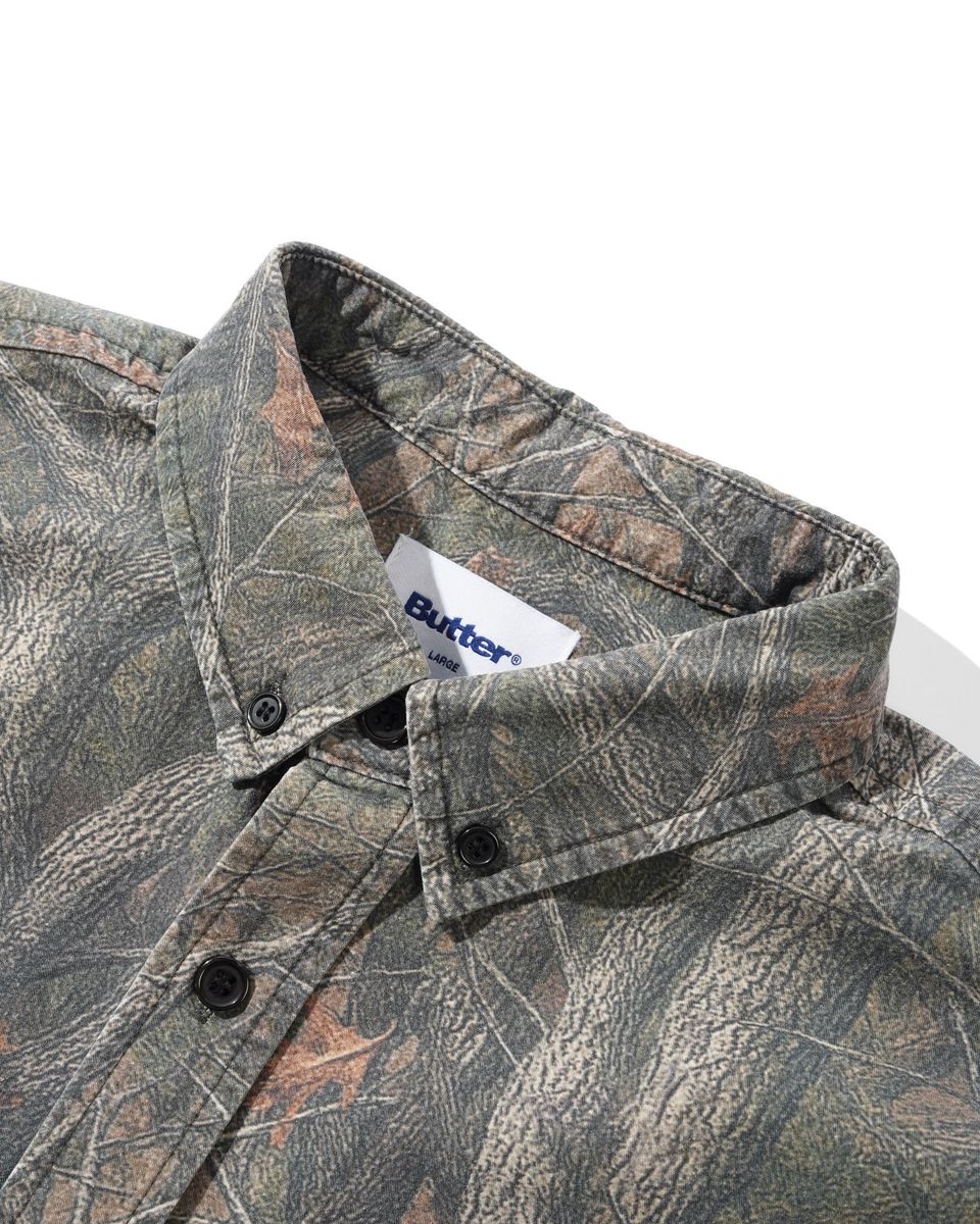 Close-up of a camouflage button-down shirt collar with a visible Butter brand tag, set against a plain white background.