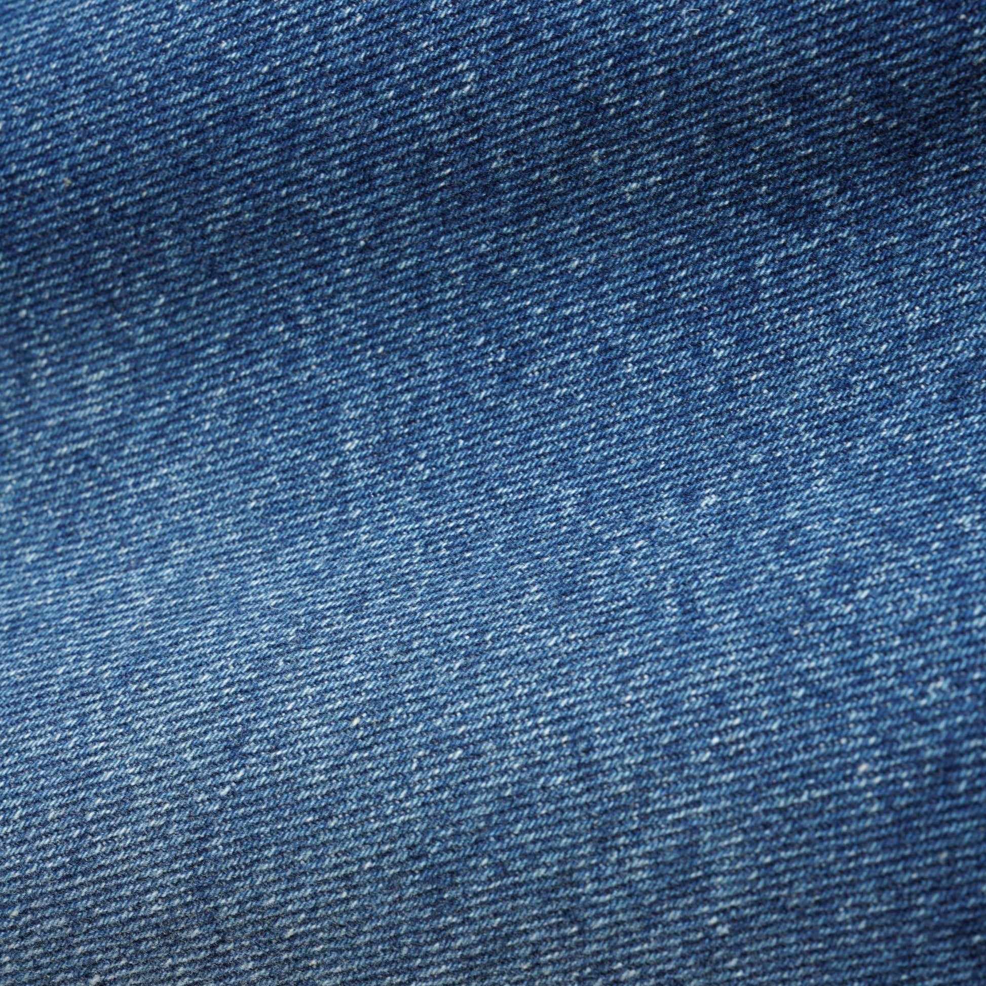 A close-up texture shot of blue denim fabric, showing the detailed twill weave and subtle fading.