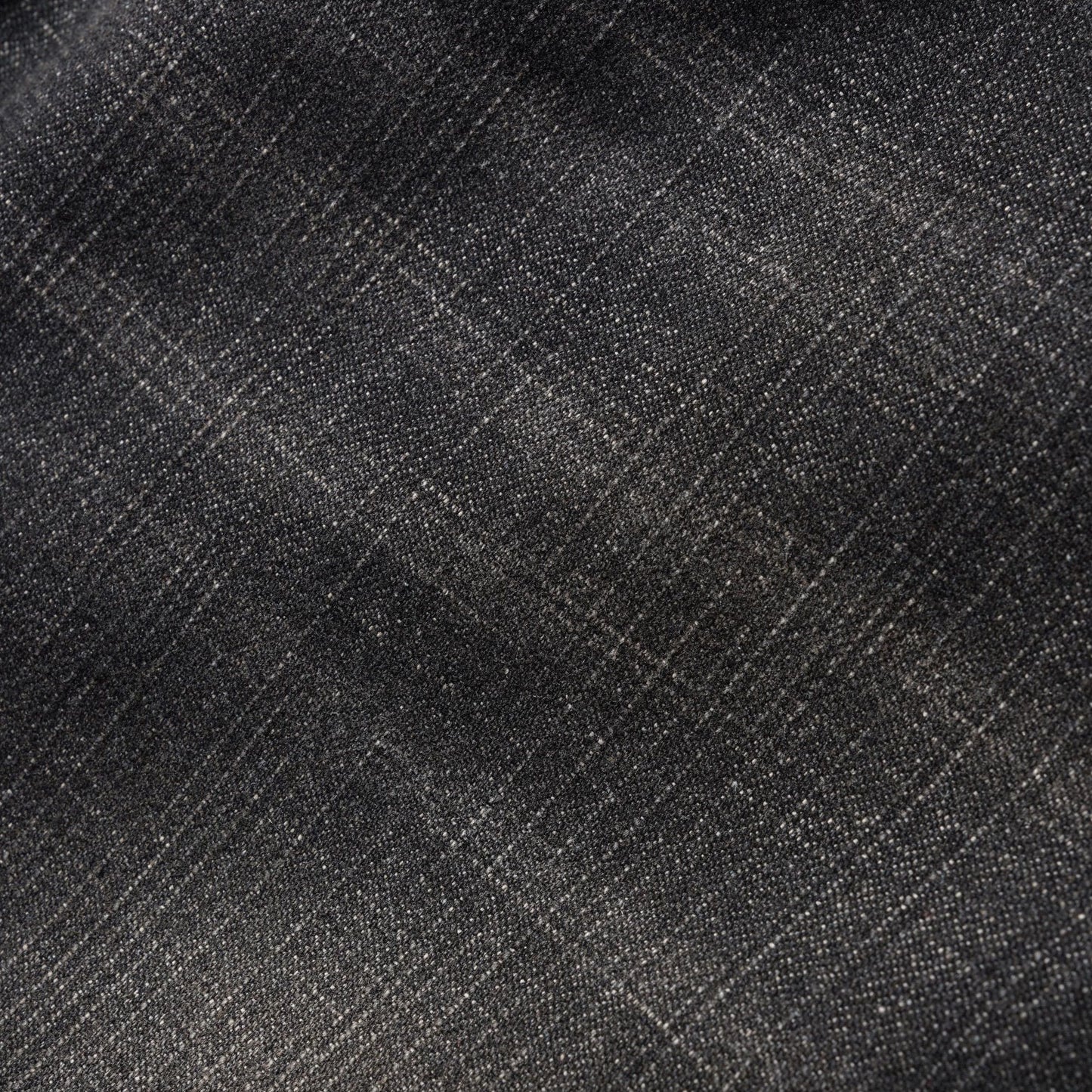 A close-up of dark charcoal gray fabric with a subtle woven texture and faint diagonal plaid lines.