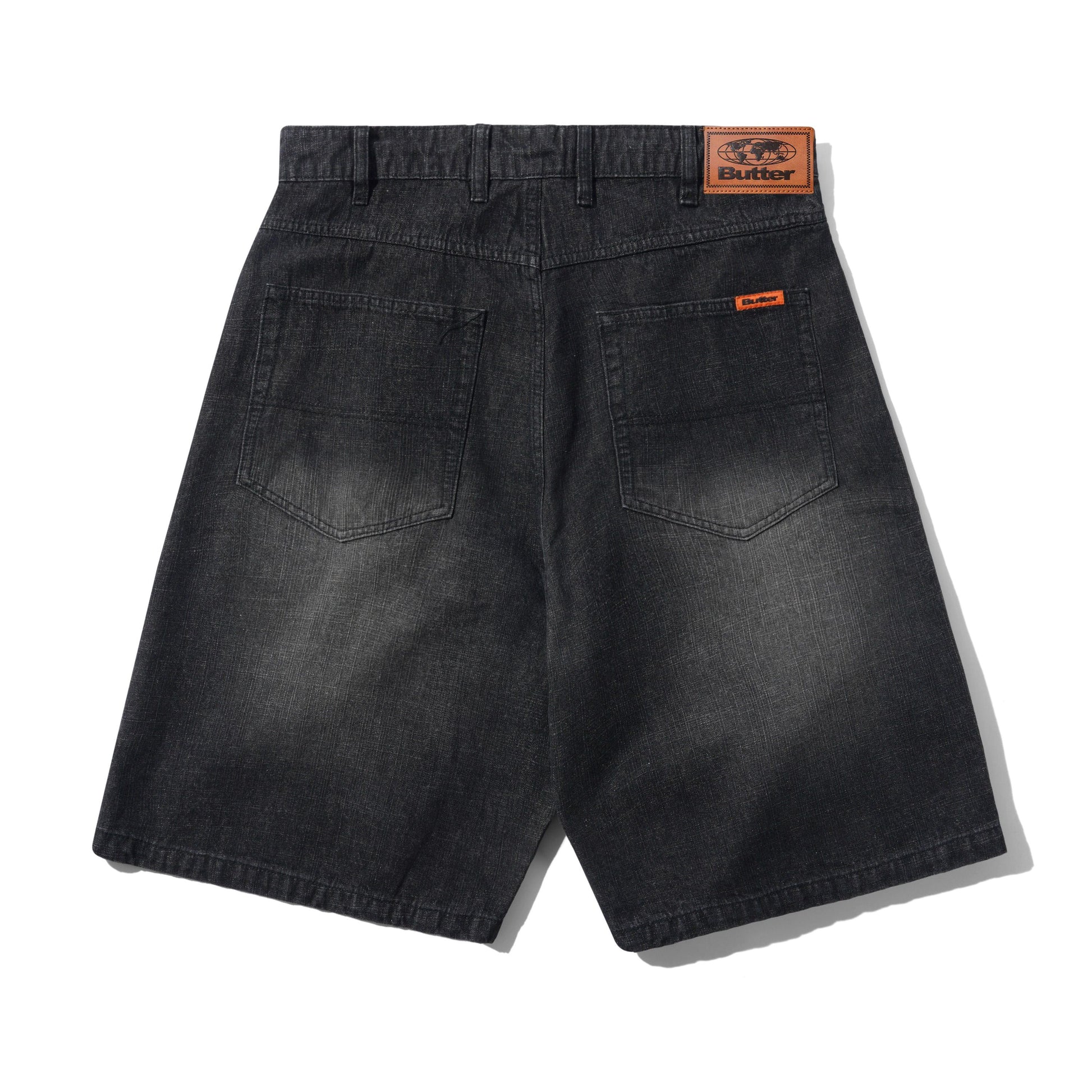Back view of dark gray washed denim shorts with a visible Butter brand patch on the waistband and a small orange brand tab on the back pocket.