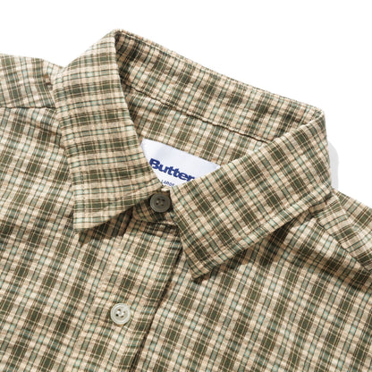 Close-up of a plaid button-down shirt collar with a white Butter brand label visible inside the neck, on a clean white background.