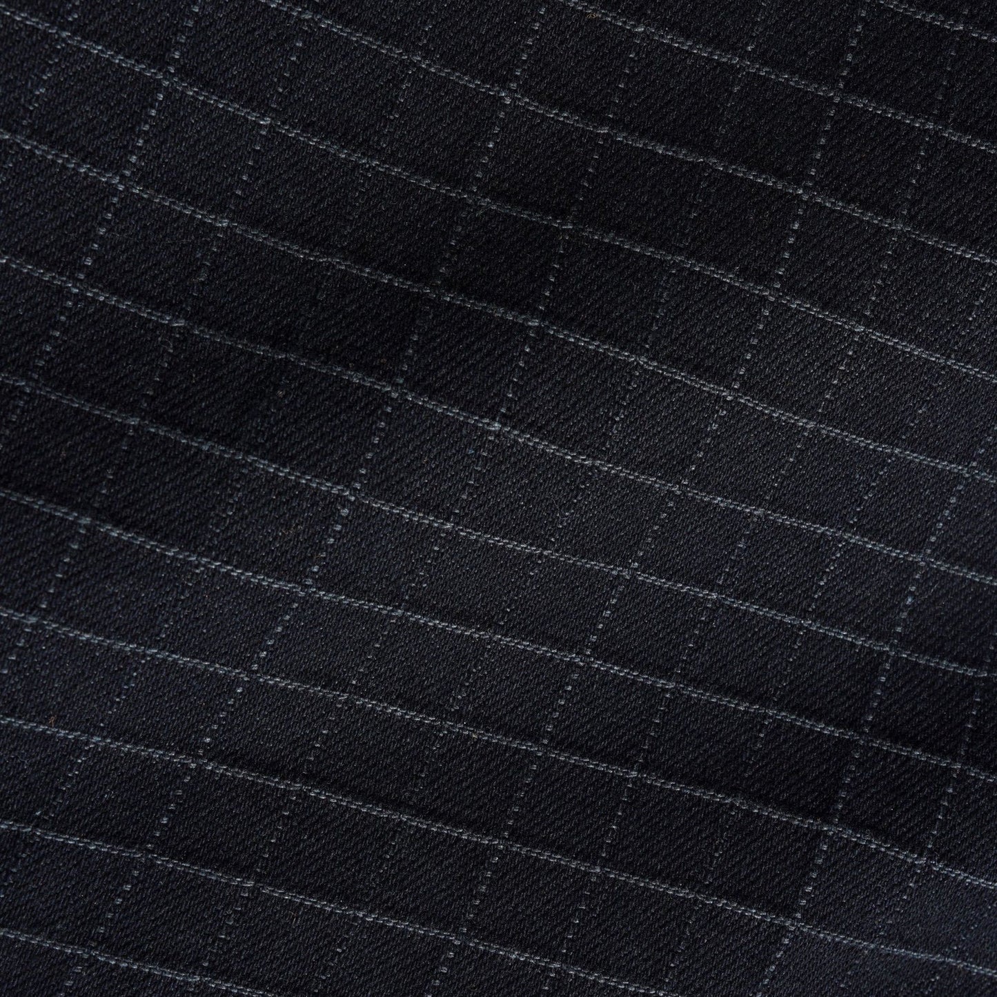 Close-up of a black fabric with a subtle windowpane check pattern in light gray.