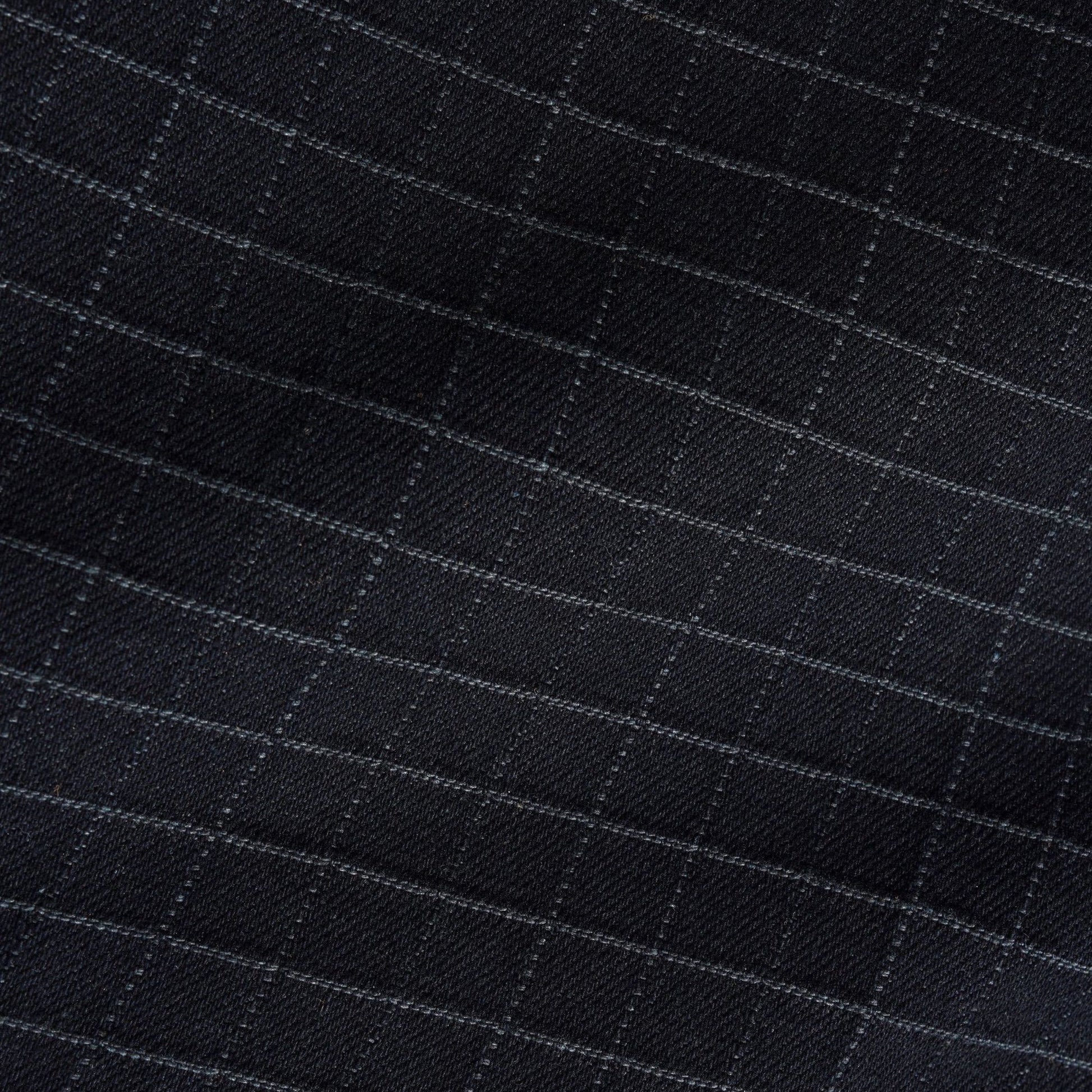 Close-up of a black fabric with a subtle windowpane check pattern in light gray.