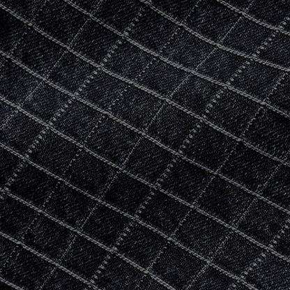 Close-up of a black fabric with a subtle diagonal grid pattern formed by lighter gray stitched lines.