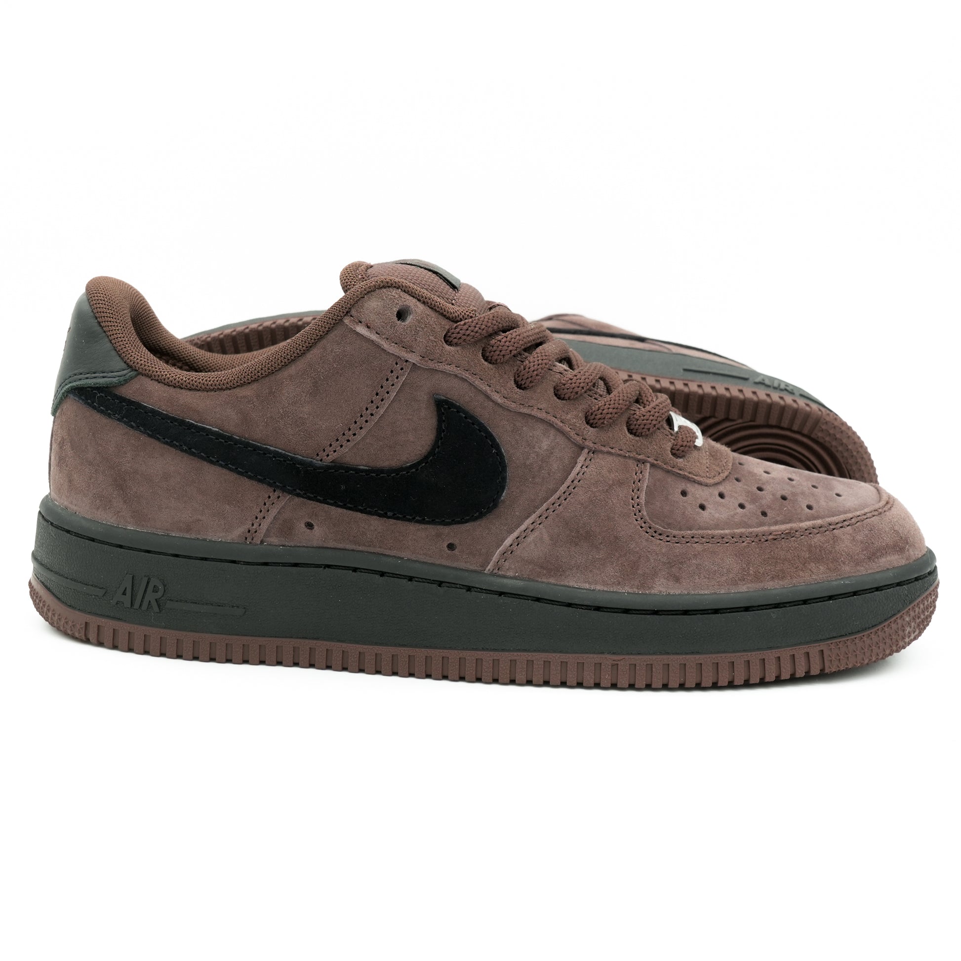 A pair of Nike Air Force 1 Low sneakers in brown suede with a black Swoosh and black accents on the heel, collar lining, and midsole.