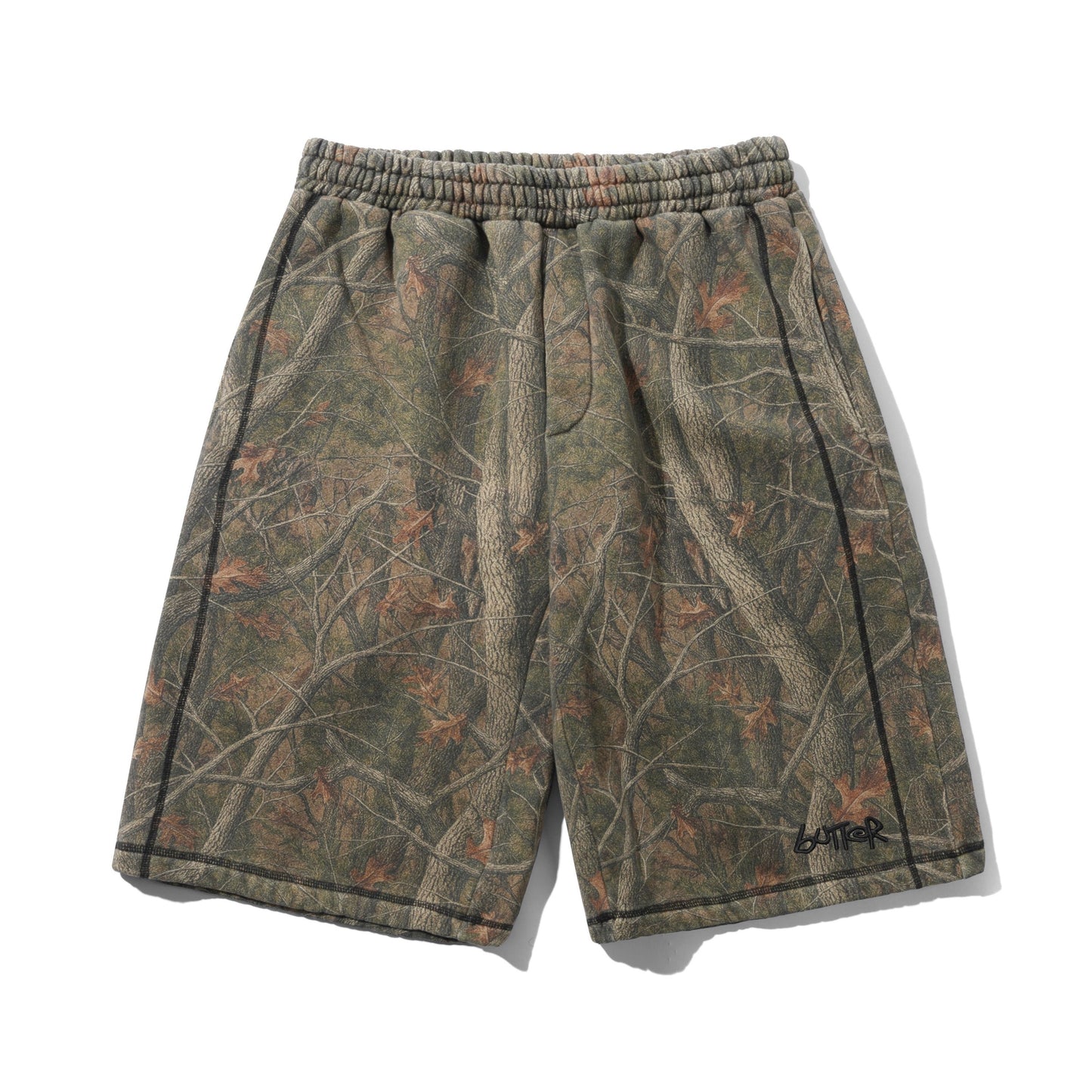 A pair of camouflage athletic shorts with a woodland tree-bark pattern in shades of green, brown, and gray, featuring a black side stripe and a black 'LATER' logo on the lower left hem.