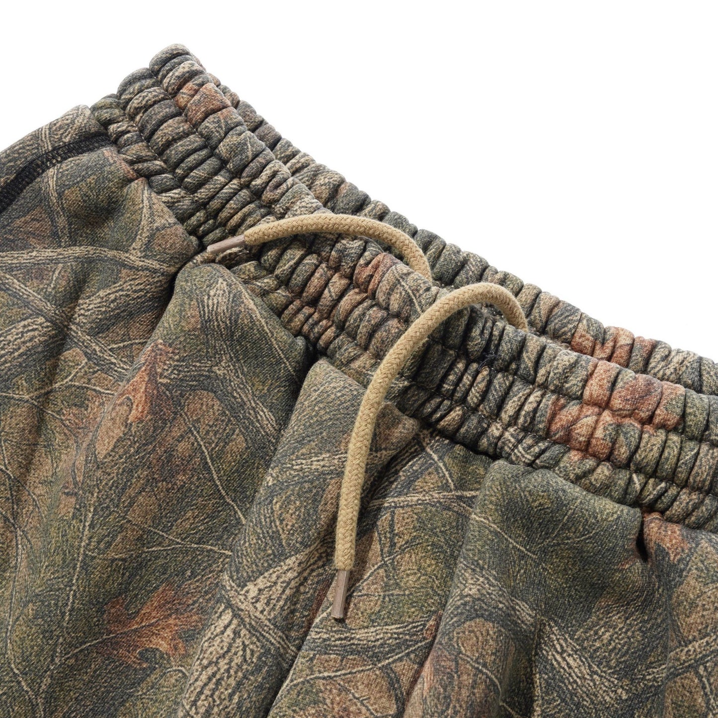 Close-up of camouflage sweatpants with a textured elastic waistband and a tan drawstring, set against a plain white background.