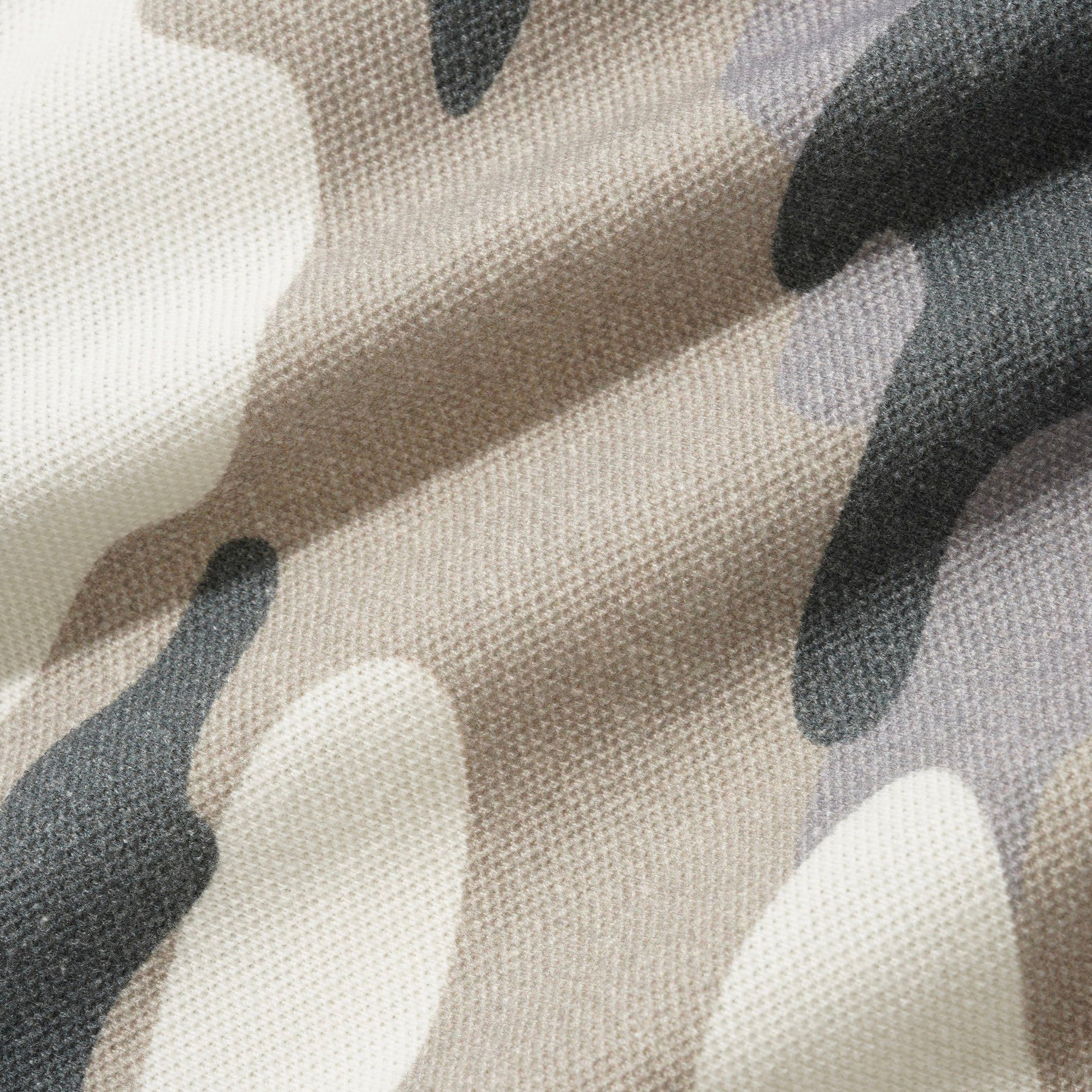 Close-up of a camouflage fabric with a textured weave, featuring organic shapes in beige, off-white, and dark gray.