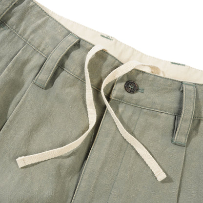 Close-up of green pants with a button and white trim on a white background
