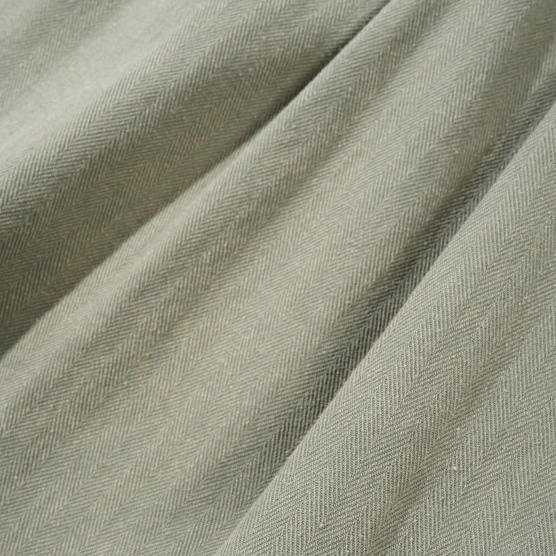 Close-up of textured green fabric with a subtle herringbone pattern