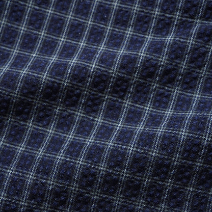 Close-up of a navy blue fabric with a white and light blue windowpane plaid pattern.
