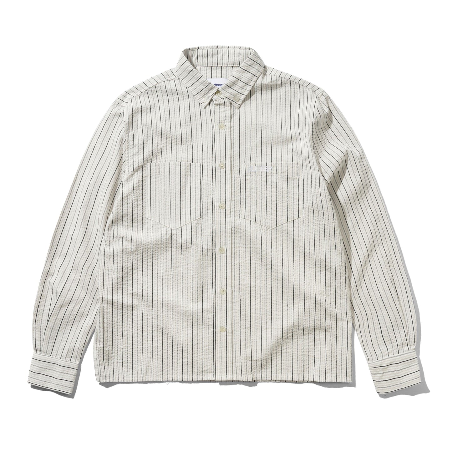 A long-sleeve button-down shirt with a textured, slightly wavy fabric, featuring vertical thin stripes in dark brown and beige on an off-white base. It has a classic collar, button-down front, and two chest pockets.