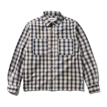 A long-sleeve button-up shirt with a classic plaid pattern in beige, white, and dark navy blue, featuring two buttoned chest pockets and a pointed collar.