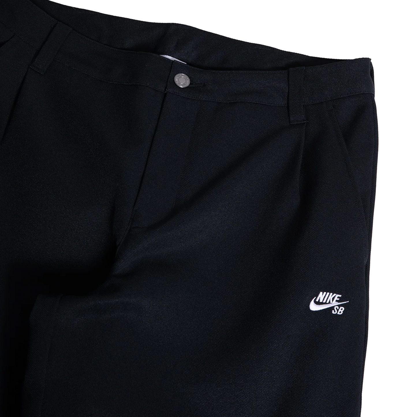 Close-up of black Nike SB pants showing the waistband, button closure, belt loops, and a white embroidered Nike SB logo on the left leg.