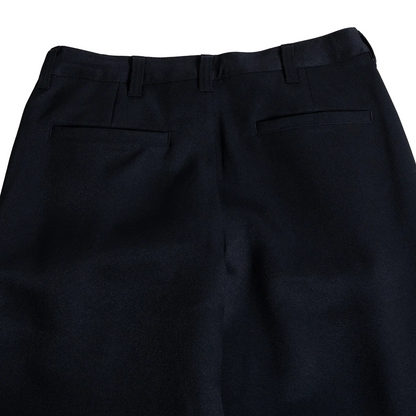 Close-up back view of black dress pants showing the waistband, belt loops, and two rear welt pockets on a white background.